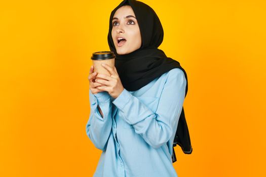 cheerful woman a glass of coffee a warming drink yellow background. High quality photo