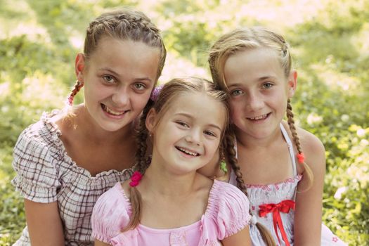 Three girls sit on the grass and smile