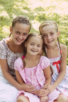 Three girls sit on the grass and smile