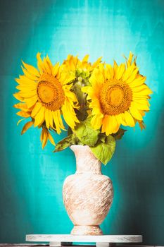 Sunflower in the vase over blue wooden background