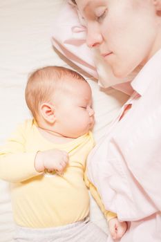 co-sleeping mother and three months baby after breastfeeding on the bed