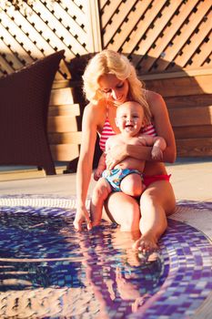 Pretty young mom with baby at the swimming pool