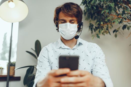 Man in medical mask working from home while coronavirus quarantine 2020
