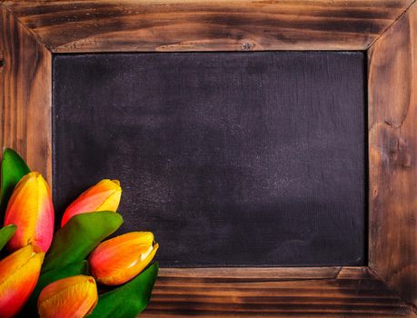 Tulips with chalkboard on a wooden background - spring greetings