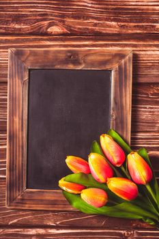 Tulips with chalkboard on a wooden background - spring greetings