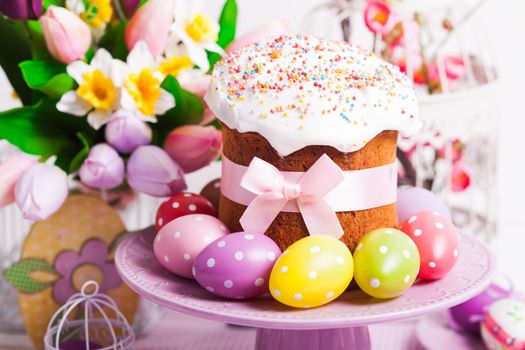 Easter cake and colorful polka dot eggs on the plate and flowers on the foreground