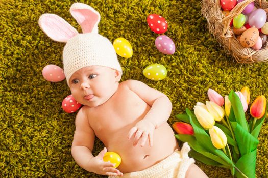 Three months baby lying on on the grass carpet as a Easter bunny