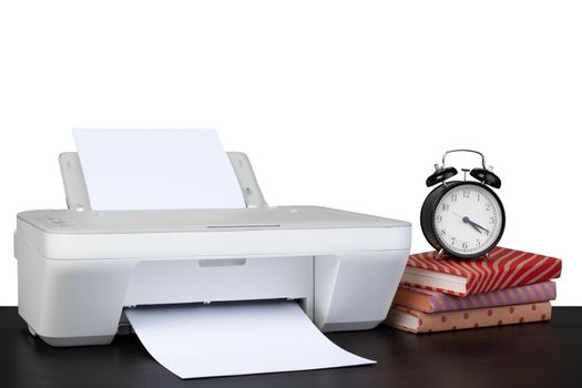 Printer and stack of books on black table against white background, close up