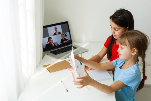 Cool online school. Kids studying online at home using a laptop. Cheerful young little girls using laptop computer studying through online e-learning system. Distance or remote learning