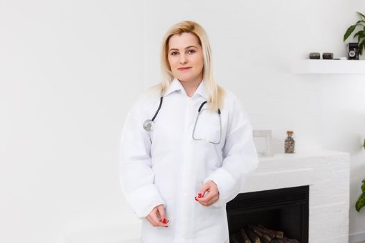 Smiling female doctor in white coat, on white