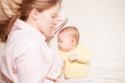 co-sleeping mother and three months baby after breastfeeding on the bed