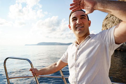 Young man in white shirt standing on the nose yacht in the open sea