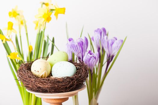Easter decorations - egg in the nest and flowers on the table