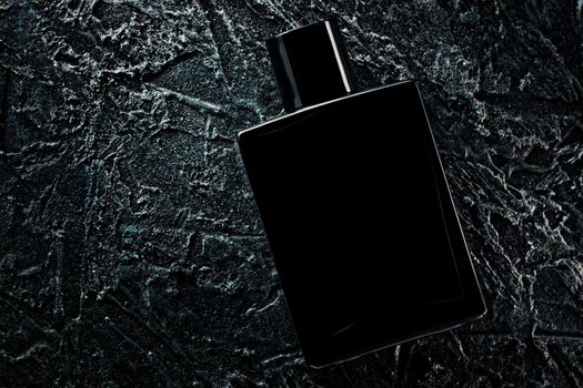 Men's fragrance of perfume or eau de toilette. Promotional photo of a black bottle on a dark background. Layout for copying text.