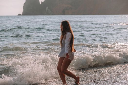 Selective focus. Happy carefree sensual woman with long hair in black swimwear posing at sunset beach. Silhouette of young beautiful playful positive woman outdoor. Summer vacation and trip concept.