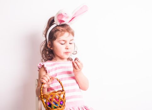 Girl eats a chocolate little eggs after Easter hunting