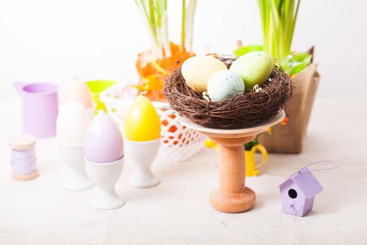 Easter decorations - egg candles, nest and flowers on the table