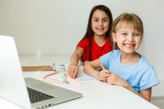 Two cute little sisters study together at home. Education for kids.