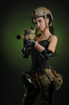 girl in military overalls airsoft posing with a gun in his hands on a dark background in the haze