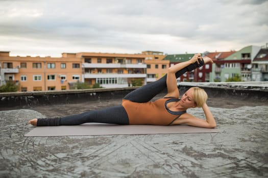 Woman enjoys practicing yoga on the roof of a building.