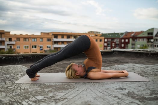 Woman enjoys  practicing yoga on the roof,Halasana/Plow pose