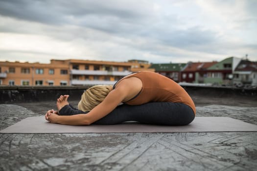 Woman enjoys practicing yoga on the roof,Paschimottanasana/Seated forward bend