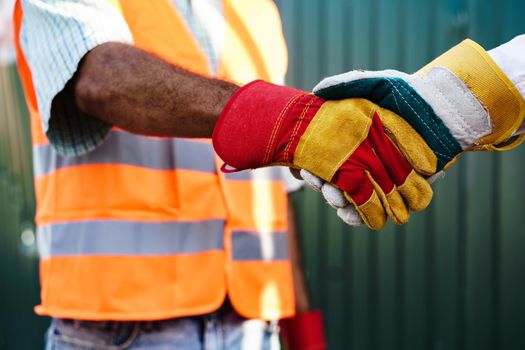 Close up photo photo of two men builders in workwear shaking hands