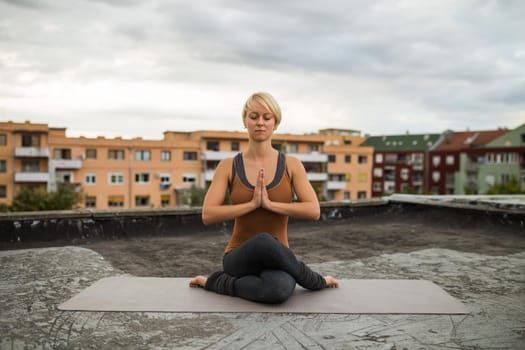 Woman enjoys  practicing yoga on the roof of a building.
