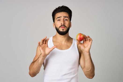 a man in a white t-shirt apples in hands fruit healthy food light background. High quality photo