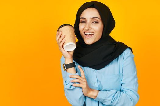 woman in black hijab with clock in hands technology emotions yellow background. High quality photo