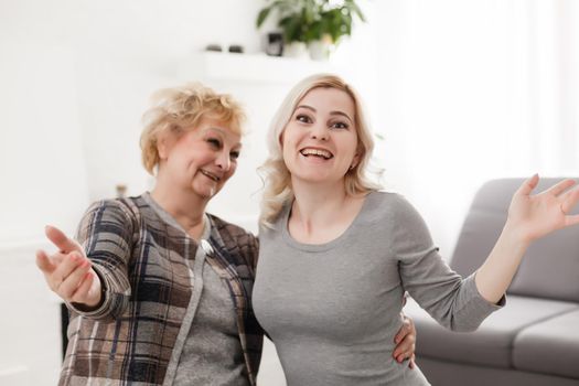 Self portrait of pretty charming positive funky mother and daughter shooting selfie on front camera having video-call sitting in modern white living room enjoying meeting free time