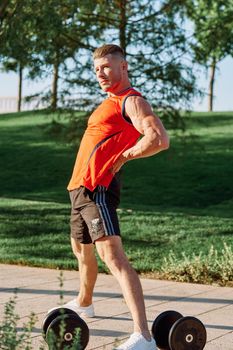 sporty man in the morning in the park with dumbbells exercise. High quality photo