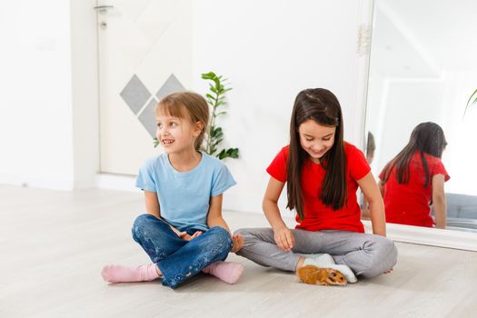 two little girls play with a hamster