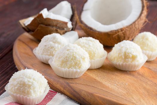 White chocolate candies with coconut topping close up on wooden table