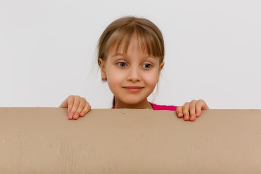 Cute little girl standing in large cardboard box, wanting to play hide-and-seek