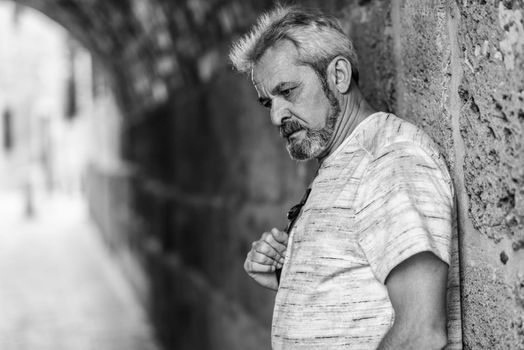 Portrait of a mature man with grey hair in urban background. Senior male with white hair and beard wearing casual clothes.