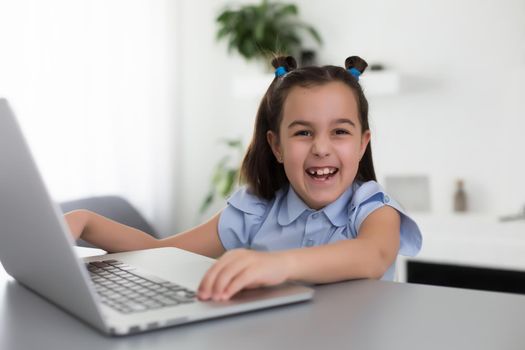 cheerfully cute girl children excited using computer learning schoolwork. kid enjoy e-learning in holiday at home.