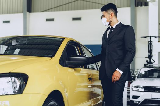 Man car dealer wearing protective medical mask on his working place, coronavirus prevention concept