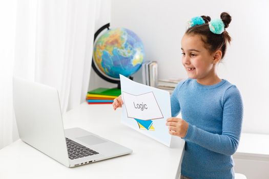 Online distance learning at home during quarantine. little girl learns logic on laptop online