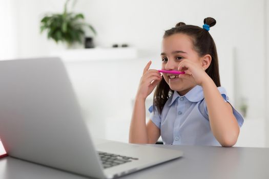 Pretty stylish schoolgirl studying homework math during her online lesson at home, social distance during quarantine, self-isolation, online education concept, home schooler