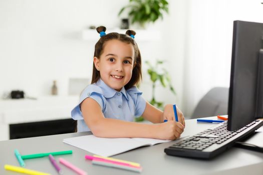 Pretty stylish schoolgirl studying homework math during her online lesson at home, social distance during quarantine, self-isolation, online education concept, home schooler