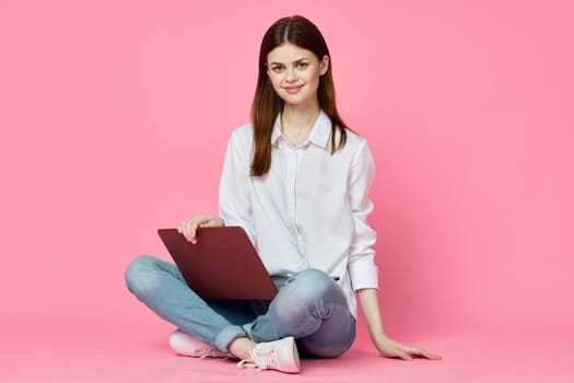 woman sitting on floor with laptop shopping entertainment pink background. High quality photo