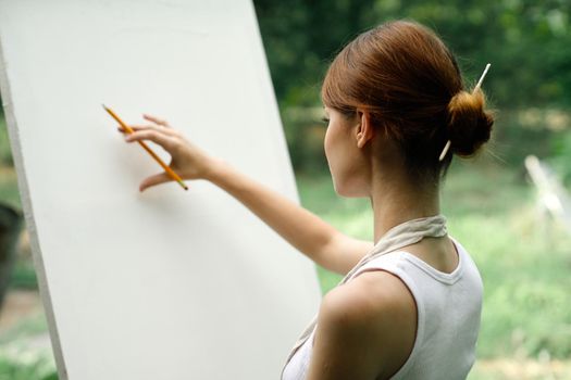 an artist in nature draws on an easel with a pencil. High quality photo