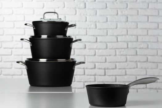 Set of cookware on table against white brick wall front view