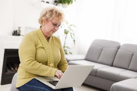 happy elderly woman using laptop computer at home