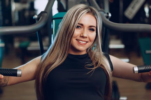 Young blonde woman fitness coach doing hands workout in a gym