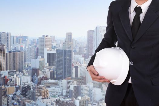 engineer holding white helmet with city background