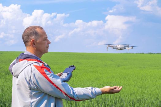 aerial photography of agricultural crops . a man with a quadrocopter on the background of a field and a blue sky. High quality photo