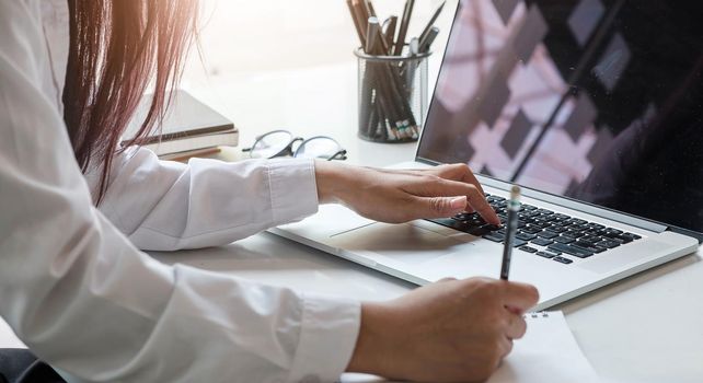 Cropped shot of an unrecognizable woman working on her laptop and paper at office..