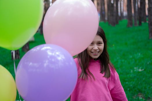 sweet tween brunette girl in pink holding colorful balloons outdoors. party, birthday concept. summertime. happy kids.